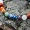 Multicolored gemstone bead bracelet displayed on a textured stone surface