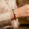 Multicolored beaded gemstone bracelet on wrist, elegant neutral shirt in background