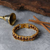 Rudraksha and gold tone bracelet on stone surface with cinnamon sticks and a brass bell