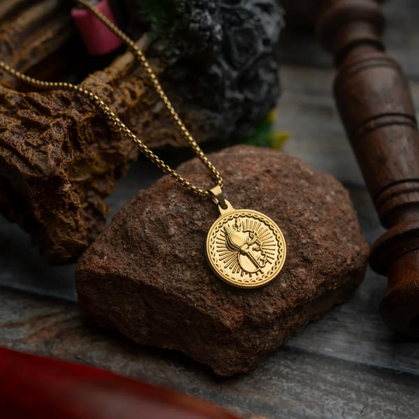 Gold pendant necklace with engraved warrior design displayed on a stone background