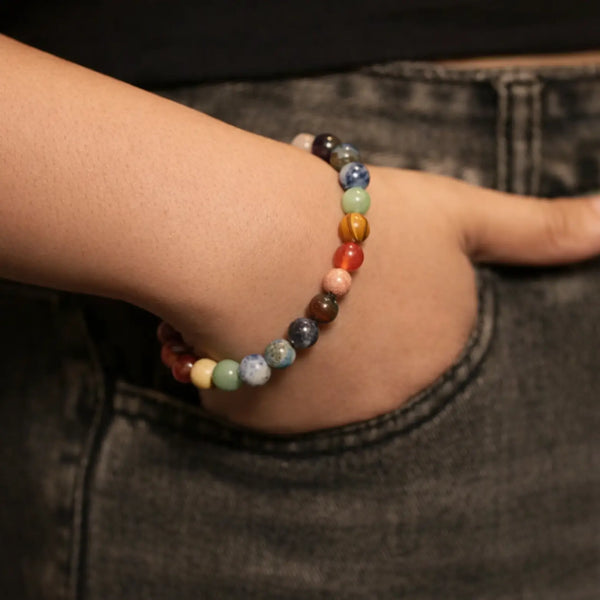 Hand in pocket wearing multicolor stone bead bracelet on wrist