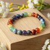 Colorful natural stone beaded bracelet on wooden block with white flowers, jewelry display