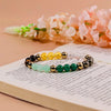 Colorful gemstone bead bracelets on open book with soft pink flowers in background