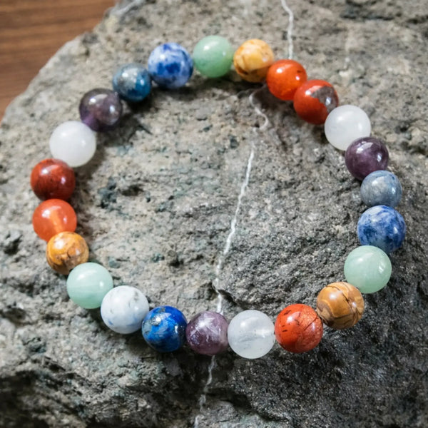 Colorful natural stone bead bracelet displayed on a textured stone background
