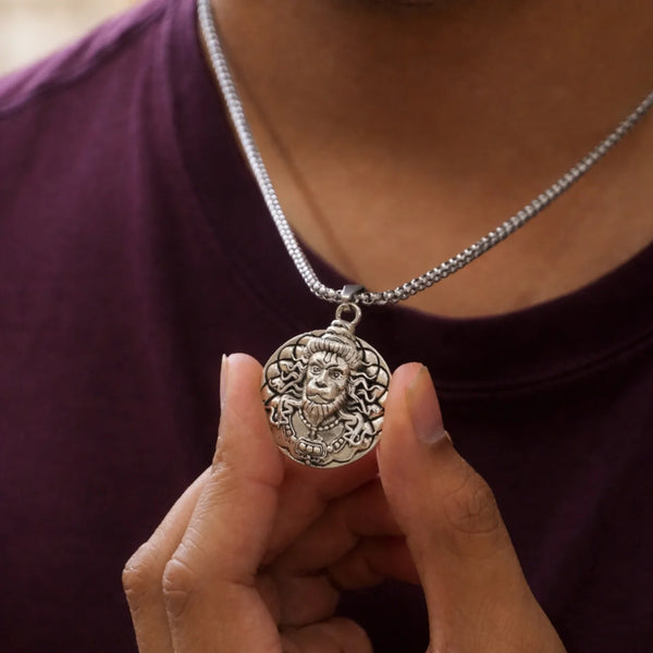 Man holding silver lion face pendant necklace with intricate engraved details