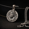 Antique silver tone pendant necklace with intricate deity face design on dark background