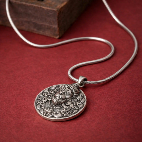 Silver oxidized pendant necklace with engraved face design on red background