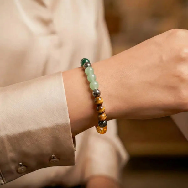 Multicolored beaded gemstone bracelet on wrist, elegant neutral shirt in background