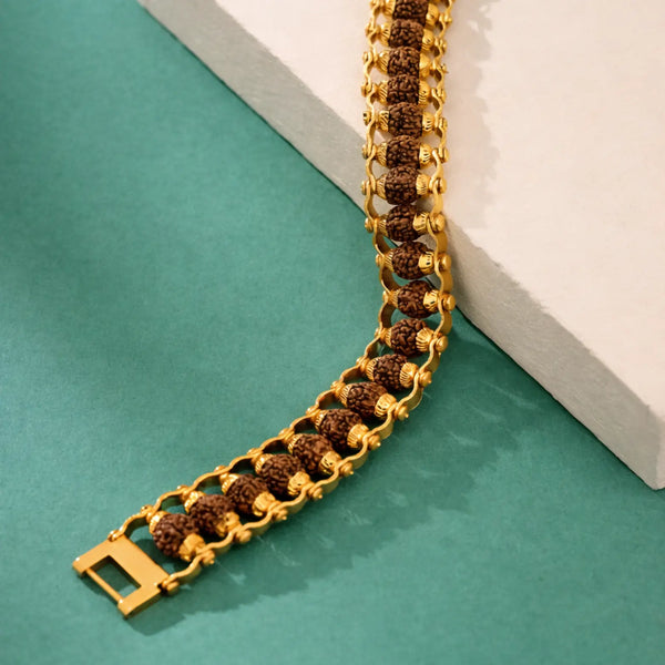Rudraksha and gold-toned chain bracelet displayed on a green and white surface