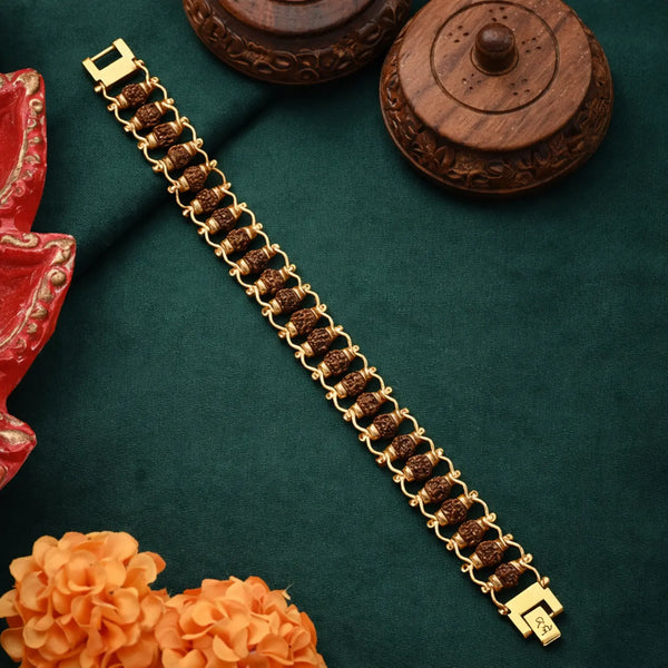 Gold plated Rudraksha bracelet with intricate links on a green fabric, floral and wooden decor