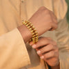 Hand wearing gold Rudraksha bead bracelet with intricate chain design