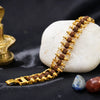 Rudraksha and gold chain bracelet displayed on white stone with decorative elements